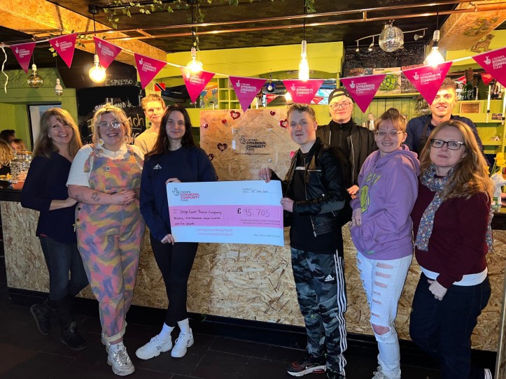 A group of people celebrating National Lottery funding with a cheque
